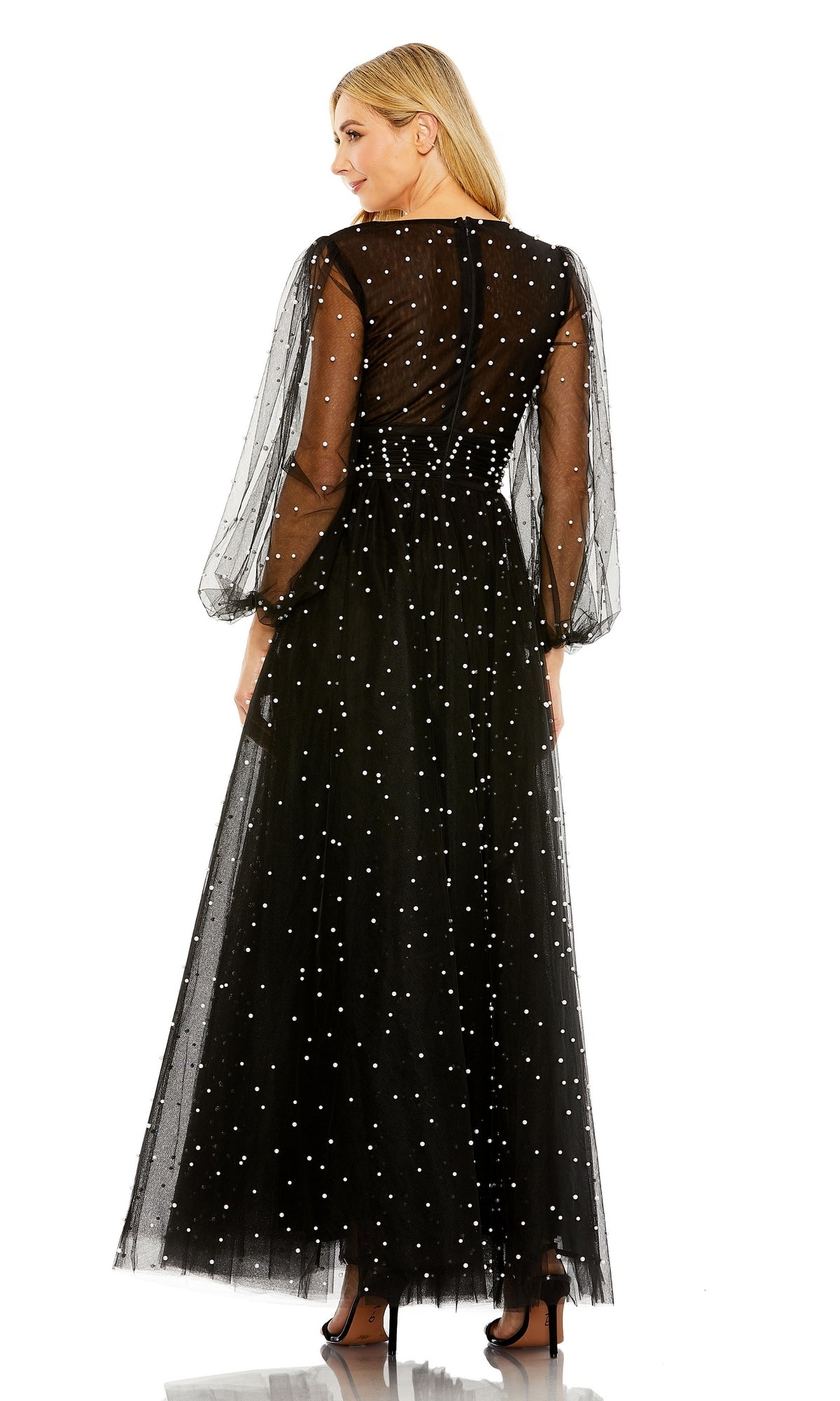 A woman stands elegantly in high heels, seen from the back in the Long Formal Dress 20746 by Mac Duggal—black with white polka dots, puffed sleeves, and a ruched bodice.